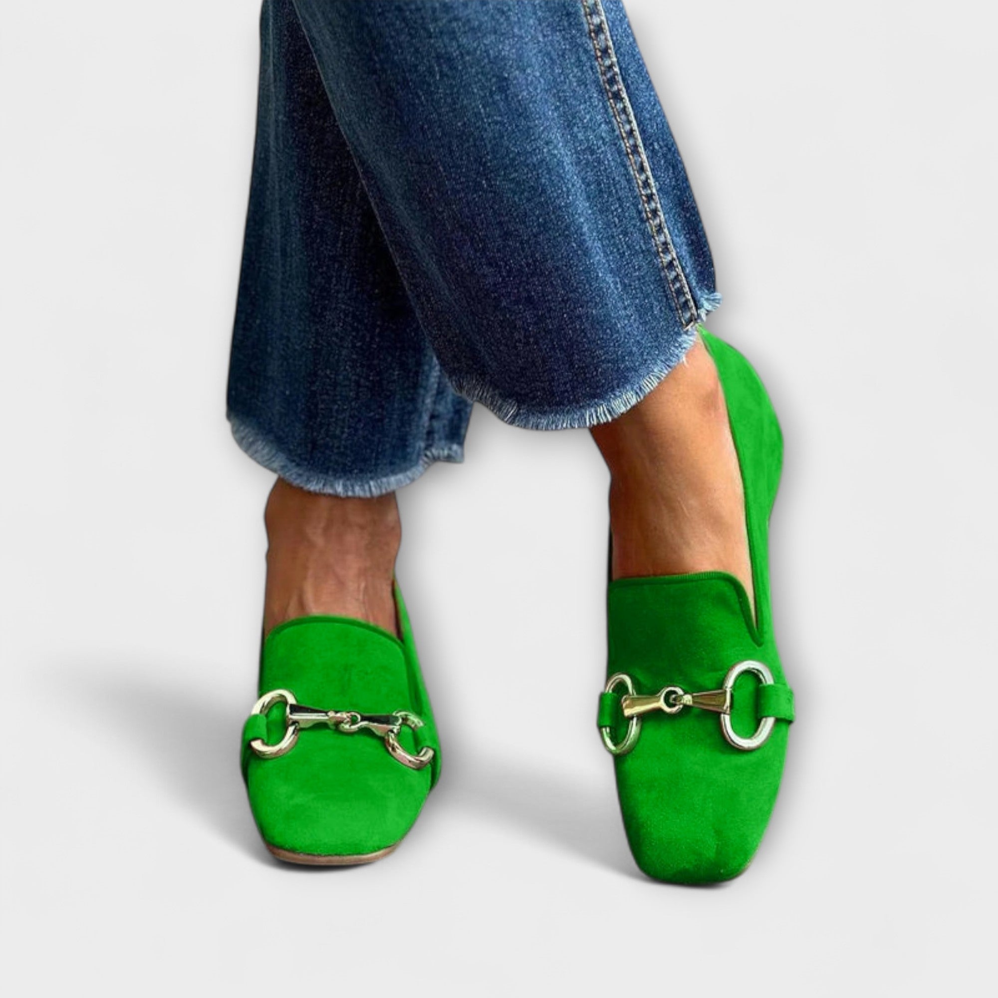 A woman wearing green slip-on loafers with a gold horsebit detail, dressed for a special afternoon.