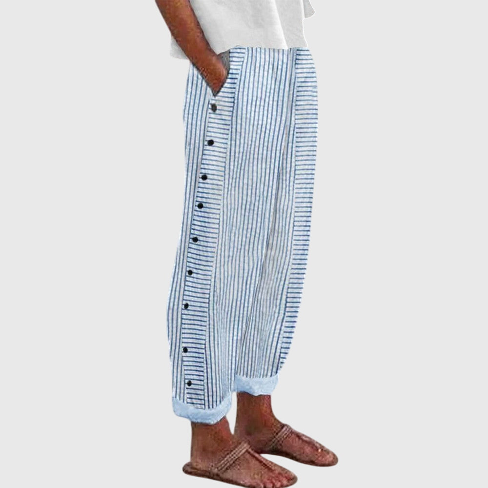 A woman wearing elegant everyday pants in a fine blue stripe with a wide cut and side buttons.