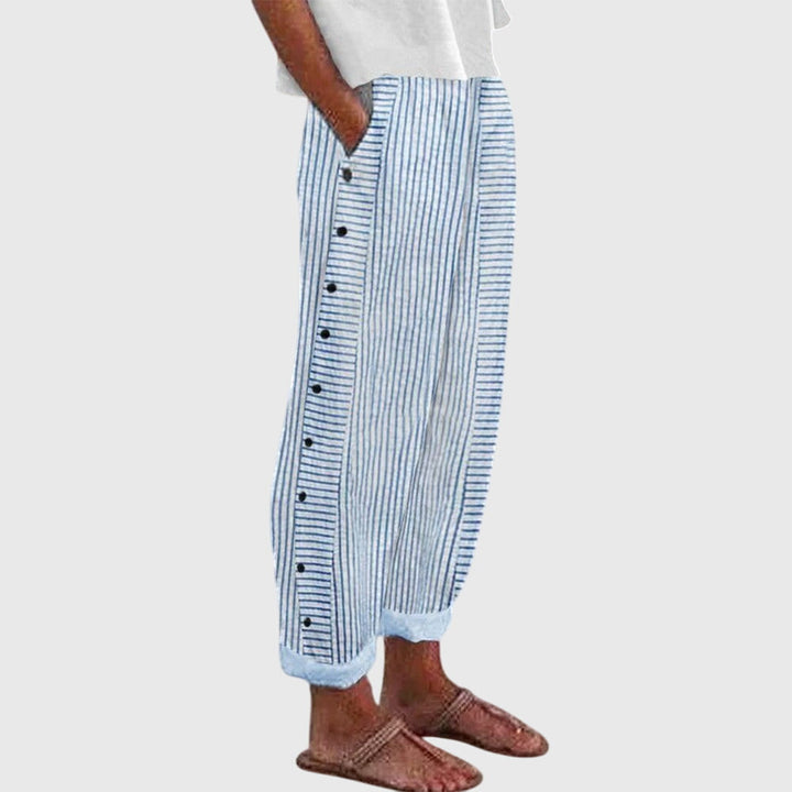 A woman wearing elegant everyday pants in a fine blue stripe with a wide cut and side buttons.