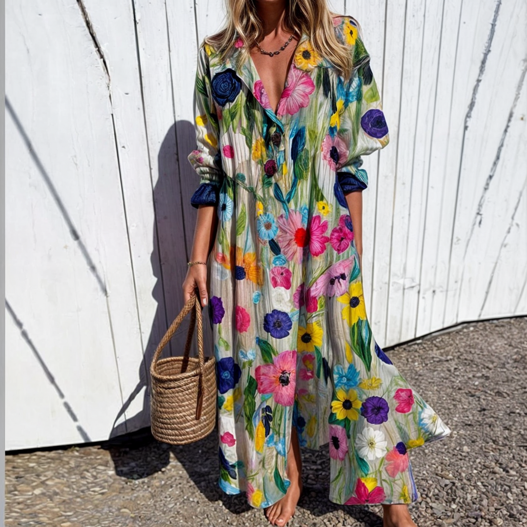 Woman wearing the Gail™ leaf print maxi dress with a button front, walking along the coast in a light breeze.