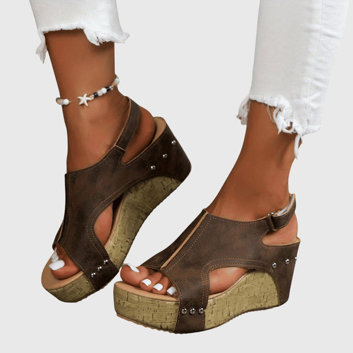 A woman in studded wedge sandals with an open front at a summer event.