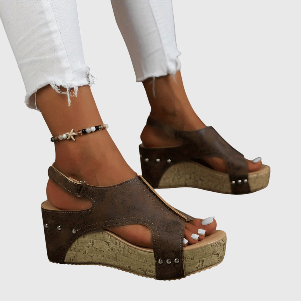 A woman in studded wedge sandals with an open front at a summer event.