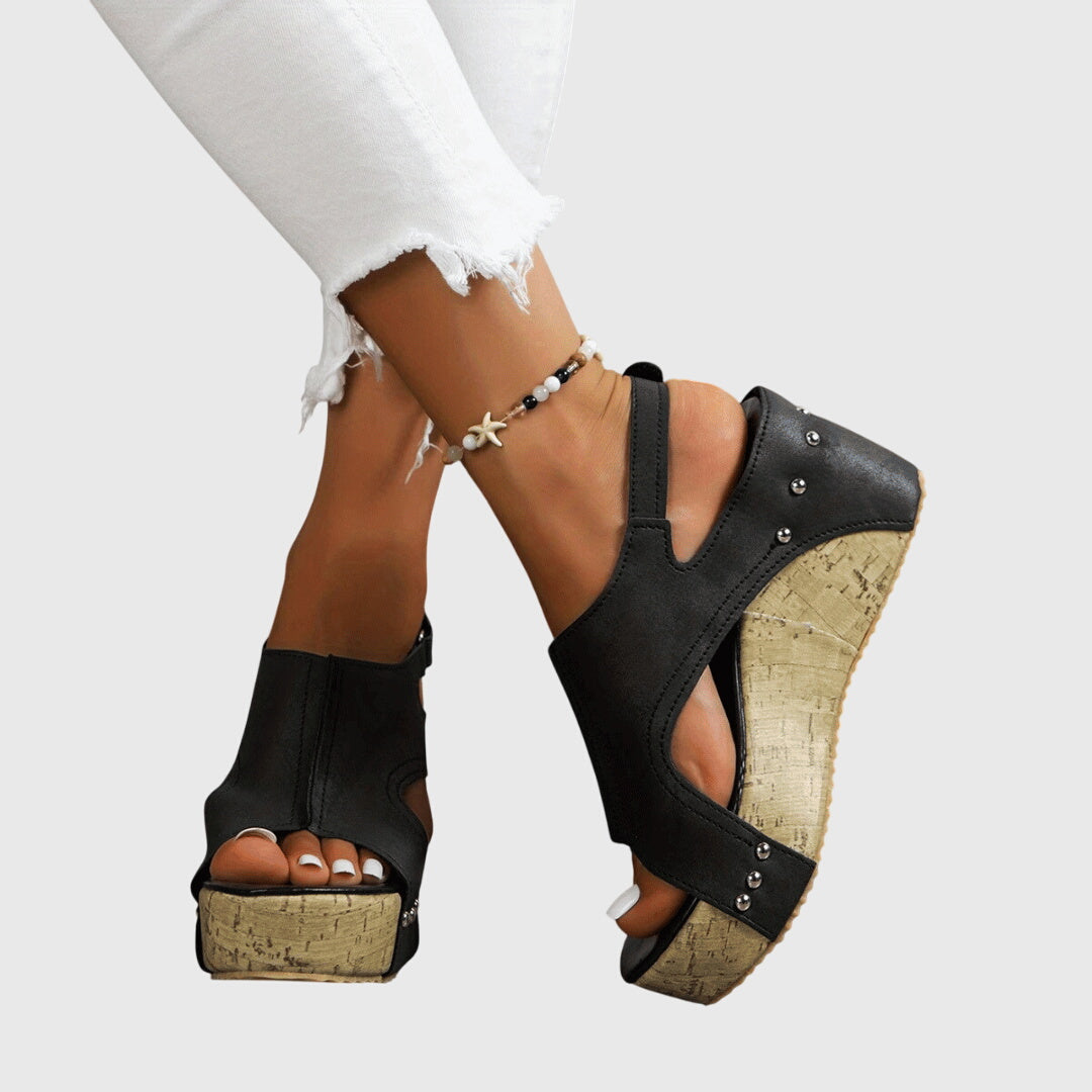 A woman in studded wedge sandals with an open front at a summer event.