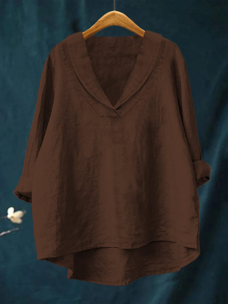 A woman wearing an elegant plain summer blouse with a flowing drape, styled with pants.