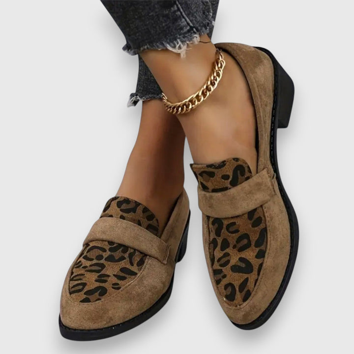 A woman wearing tan leopard print loafers with a low block heel, styled with jeans.