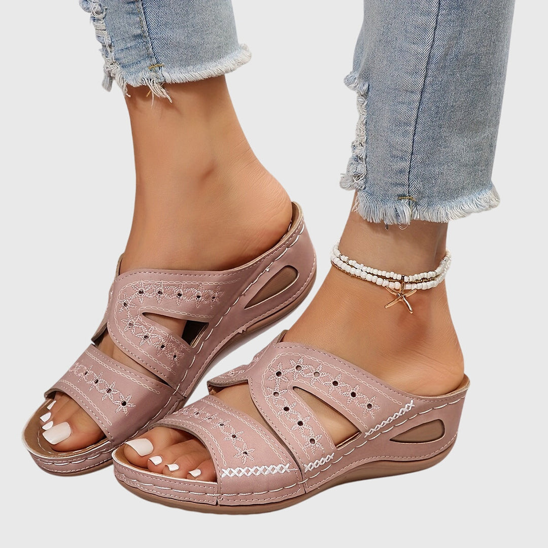 A woman walking gracefully in elegant wide-fit support sandals with an open-front design.