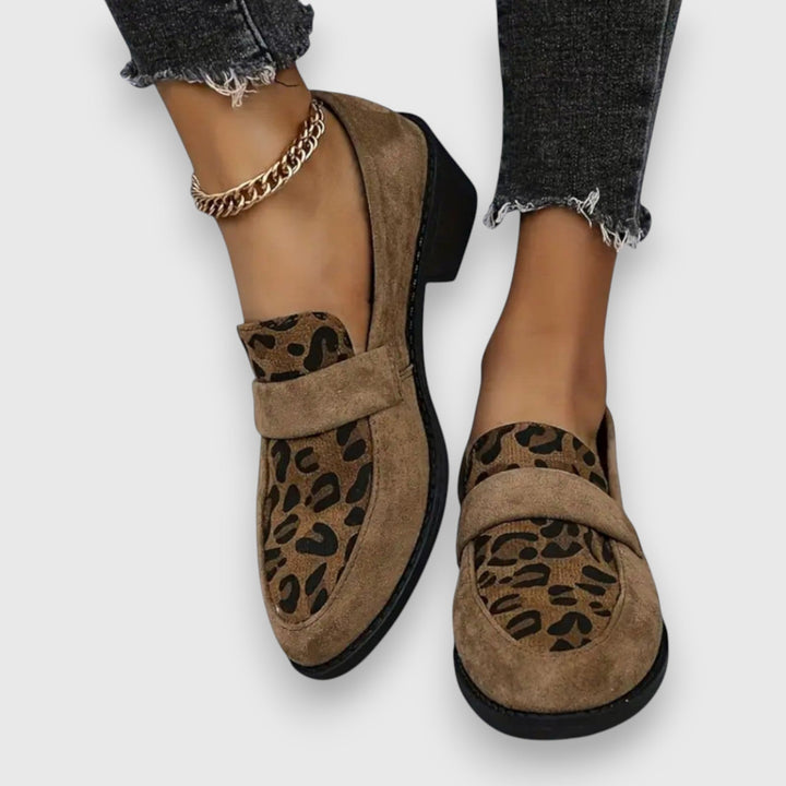 A woman wearing tan leopard print loafers with a low block heel, styled with jeans.