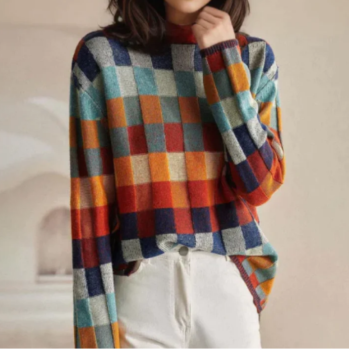 A woman wearing a colourful retro check sweater, relaxed and cosy on a cool fall morning.