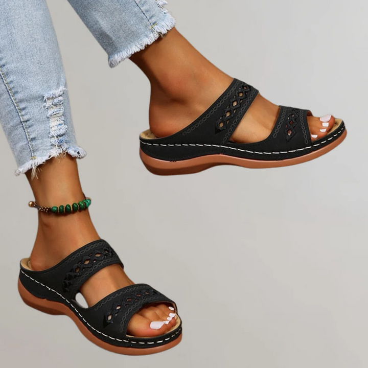 A woman walking comfortably in refined orthopaedic sandals with an adjustable strap.