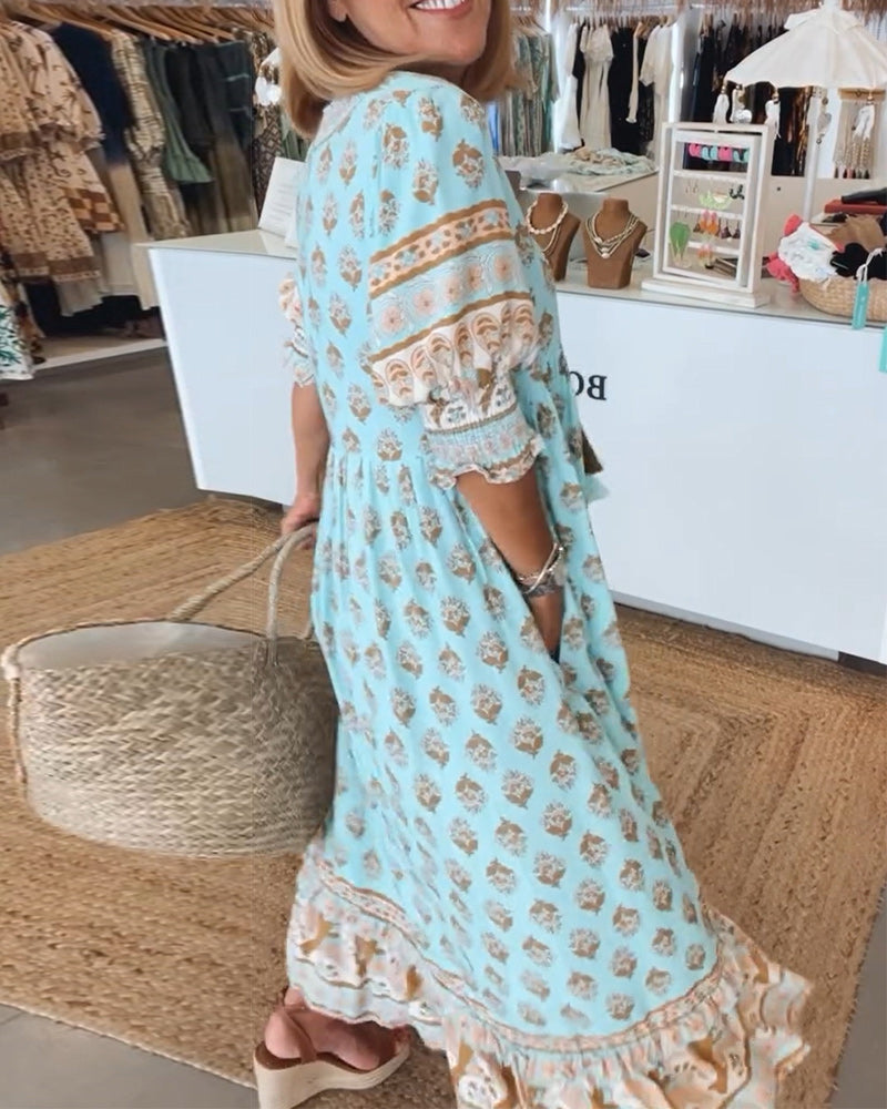 A woman wearing the Crystal boho beach dress with a flowing skirt, walking along the seaside.