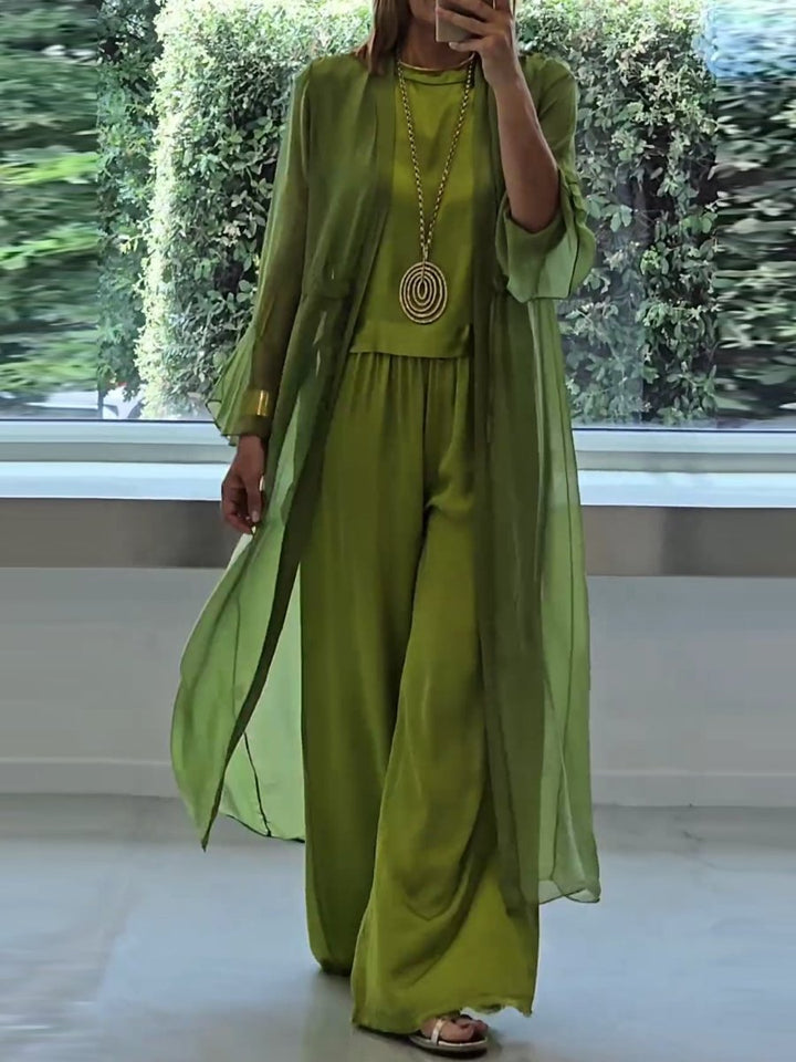 A woman wearing a flowing three-piece set with a sleeveless top, wide pants and a long cardigan.
