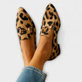 A woman wearing leopard-print loafers with a gold horsebit detail and a smart outfit