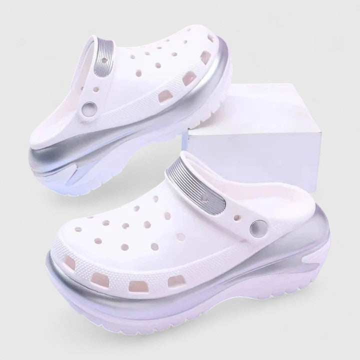 A woman walking comfortably outdoors wearing soft, cushioned orthopaedic clogs with a gentle metallic sheen.
