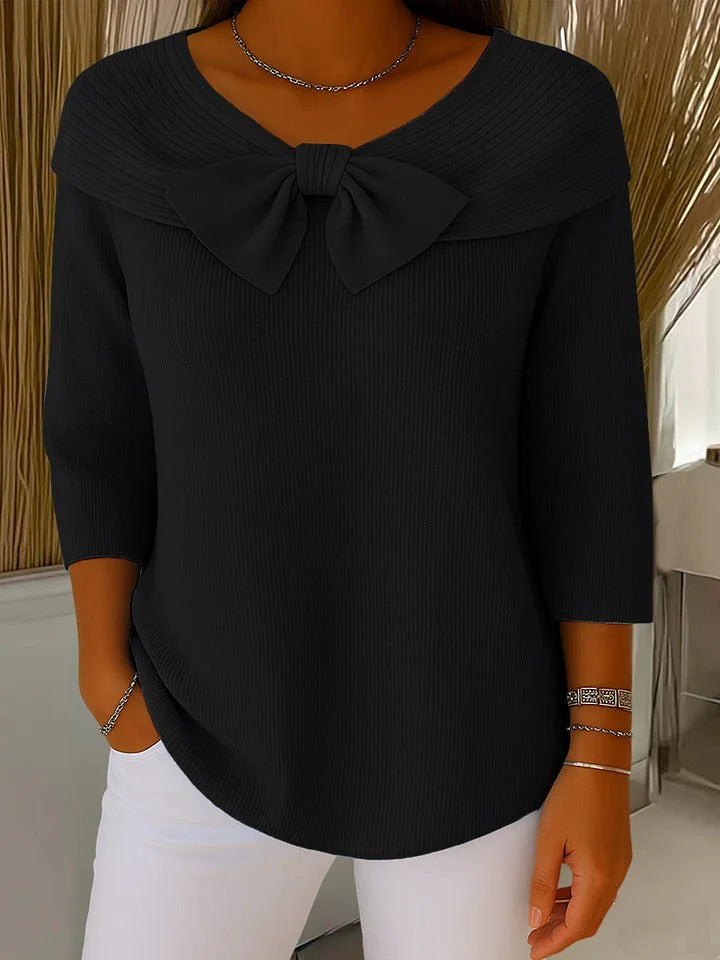 A woman wearing a shaped sweater with a soft bow detail, styled for a coffee date.