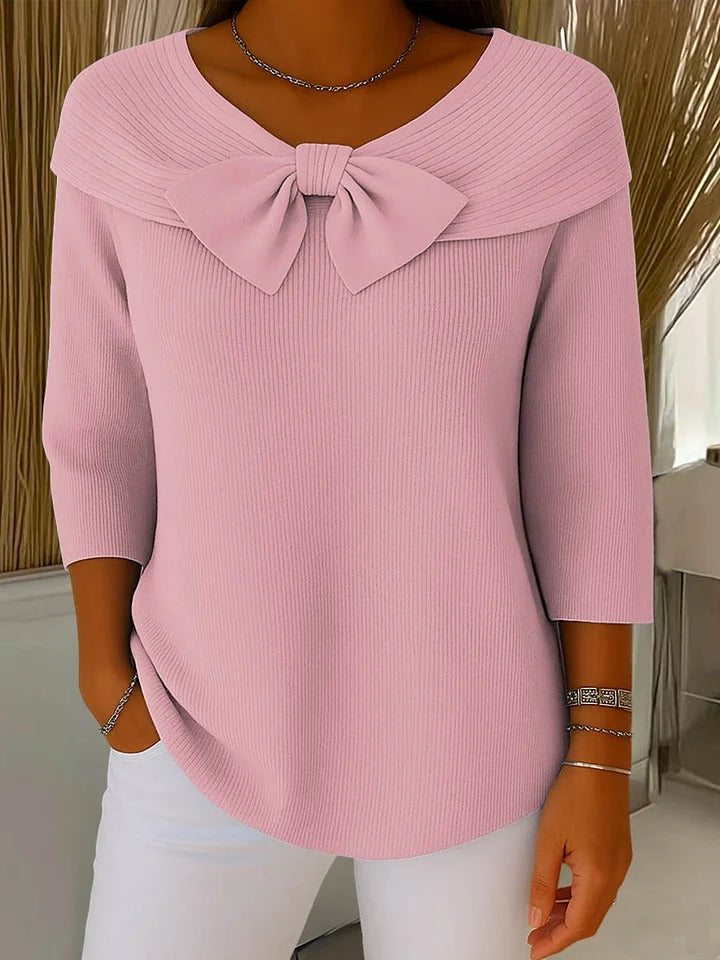 A woman wearing a shaped sweater with a soft bow detail, styled for a coffee date.