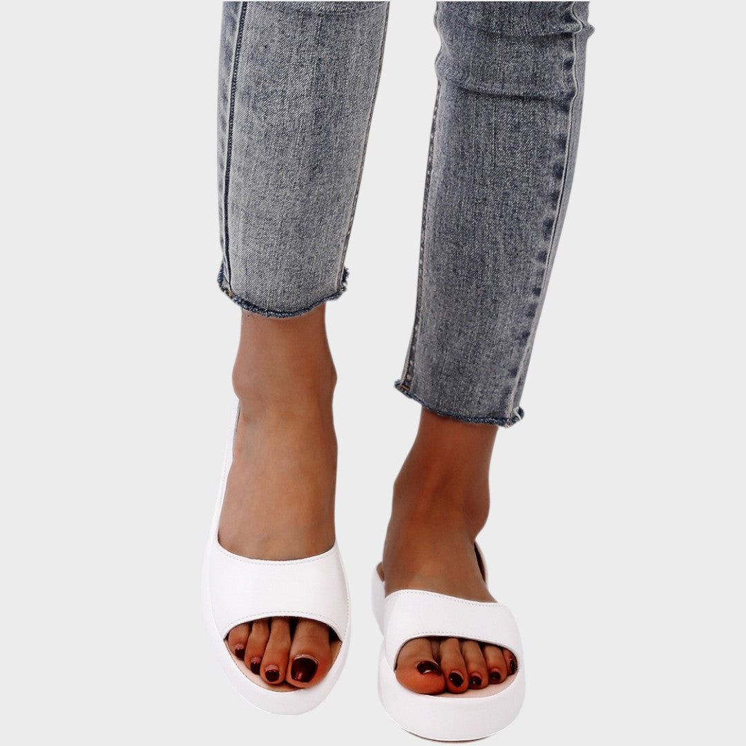 A woman walking gracefully in lightweight orthopaedic sandals with an adjustable strap on a sunny day.