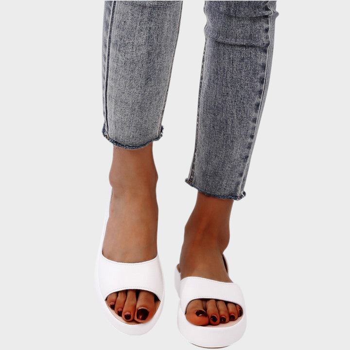 A woman walking gracefully in lightweight orthopaedic sandals with an adjustable strap on a sunny day.