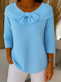 A woman wearing a shaped sweater with a soft bow detail, styled for a coffee date.