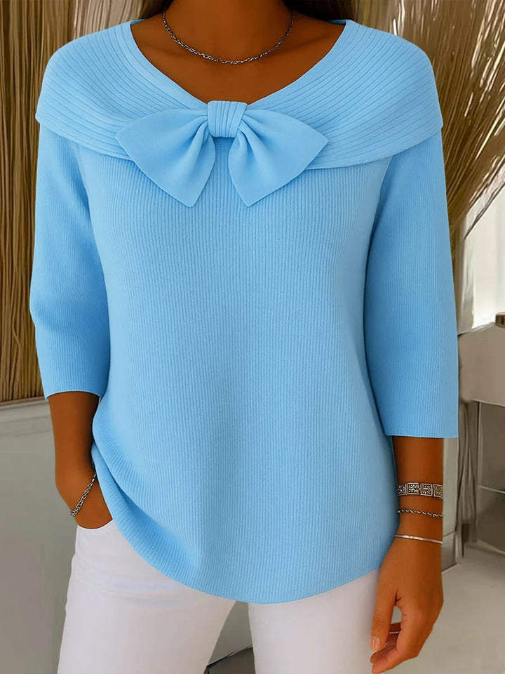 A woman wearing a shaped sweater with a soft bow detail, styled for a coffee date.