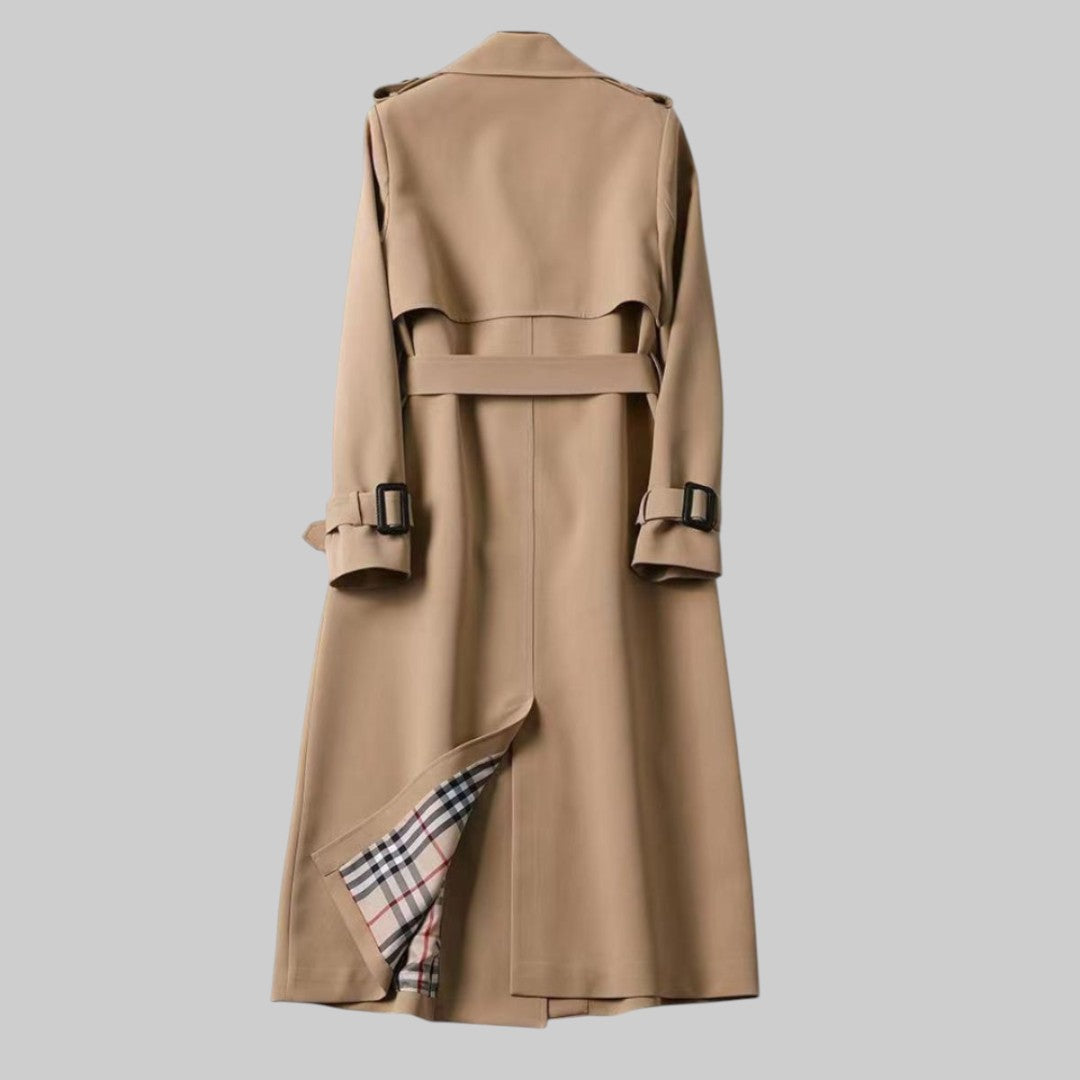A woman wearing a belted classic trench coat with a defined waist, walking through the city.