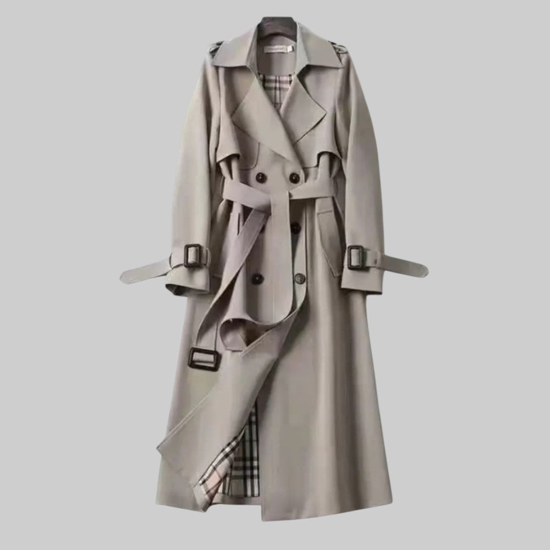 A woman wearing a belted classic trench coat with a defined waist, walking through the city.