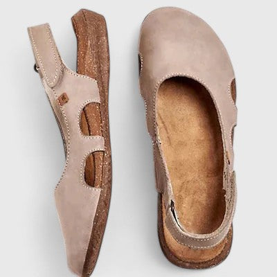 A woman wearing soft grey cut-out comfort sandals with an adjustable back strap on a relaxed weekend.