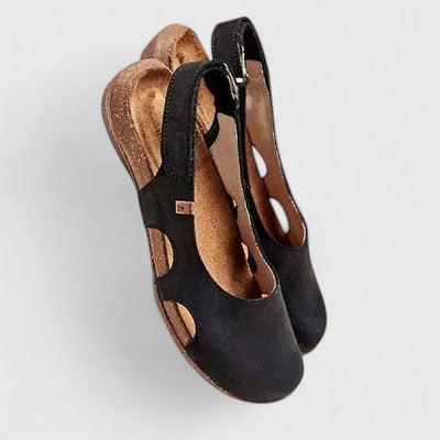 A woman wearing soft grey cut-out comfort sandals with an adjustable back strap on a relaxed weekend.
