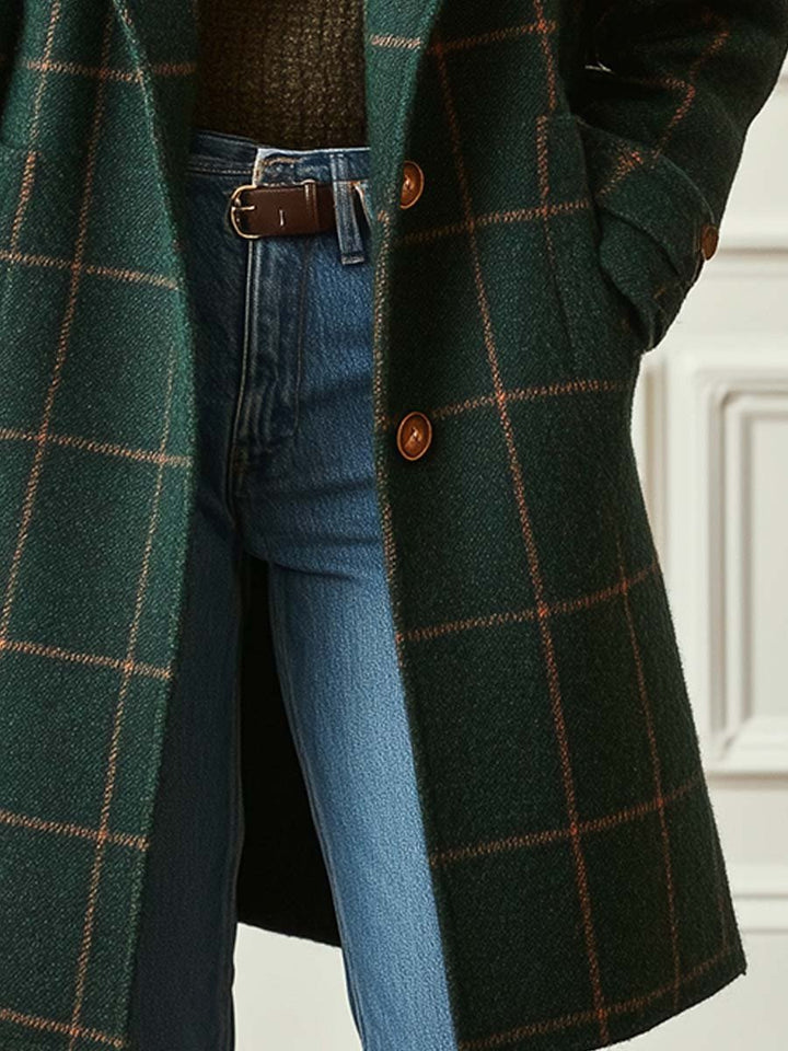 A woman wearing a dark green coat with a rust windowpane check, wide lapels and a button-through front.