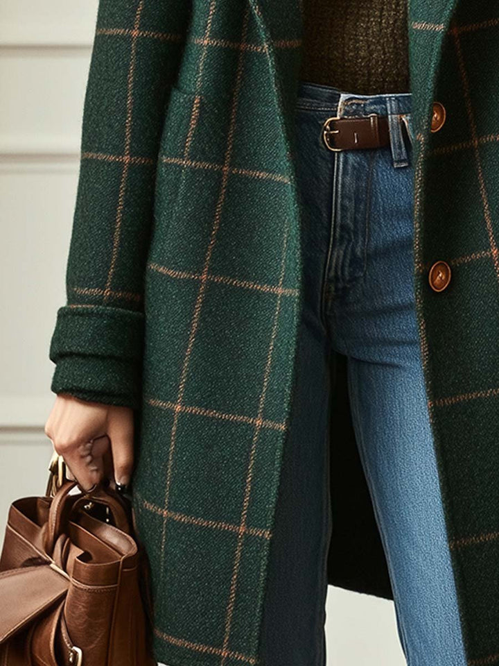 A woman wearing a dark green coat with a rust windowpane check, wide lapels and a button-through front.