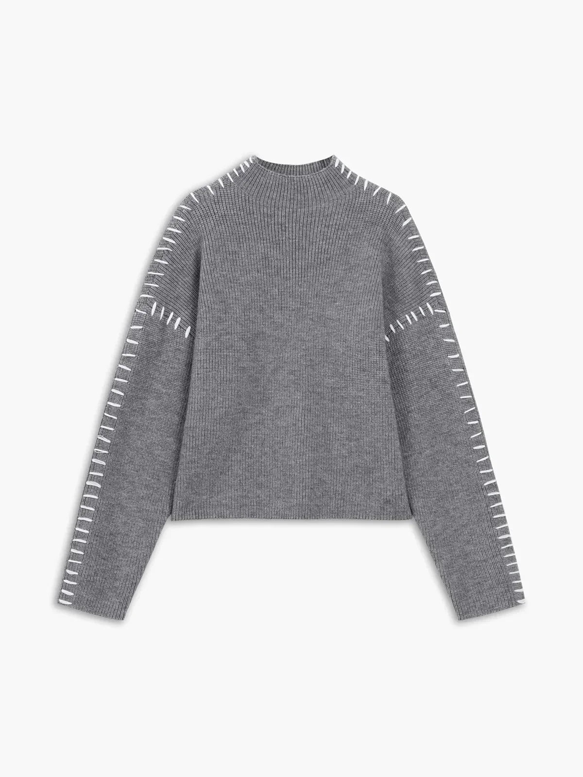 A woman wearing an oversized mock-neck sweater with whipstitch detailing, cosy and stylish.