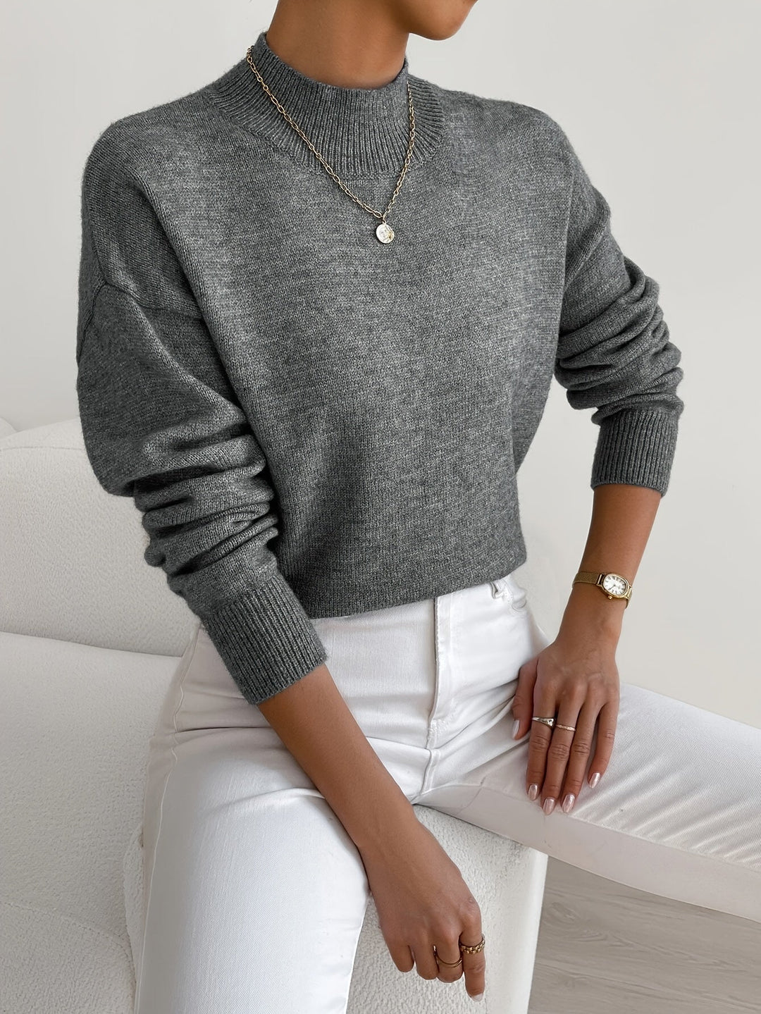 A woman wearing an elegant warm sweater with a modern stand collar, soft and refined.