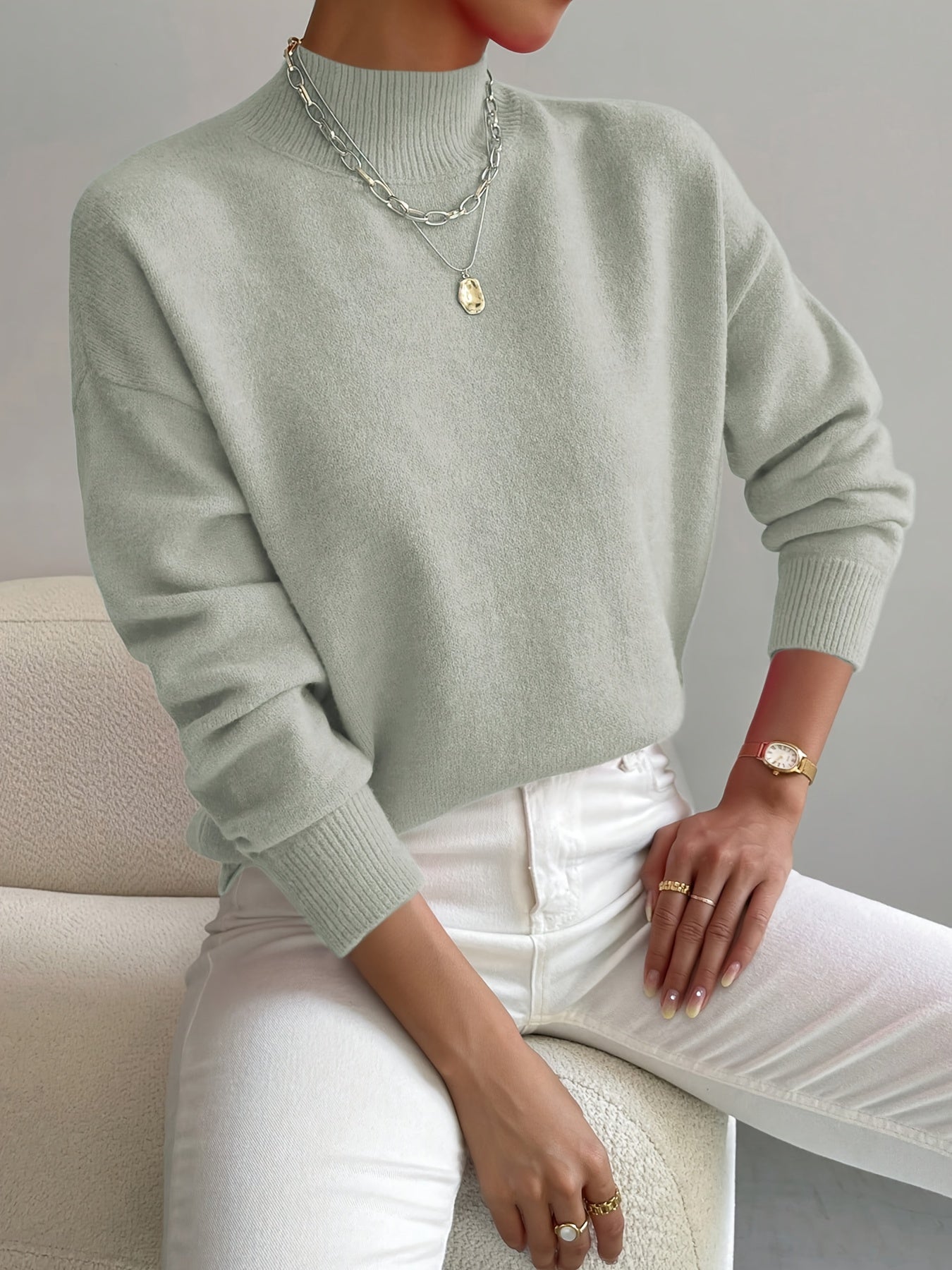 A woman wearing an elegant warm sweater with a modern stand collar, soft and refined.