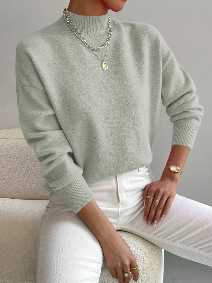 A woman wearing an elegant warm sweater with a modern stand collar, soft and refined.