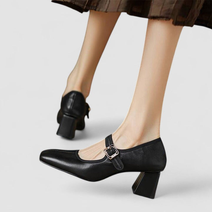 A woman in black Mary Jane shoes with a mid block heel, confident on an evening out.