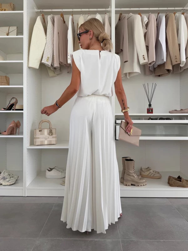 A woman wearing a structured sleeveless top with high-waisted pleated wide-leg pants.