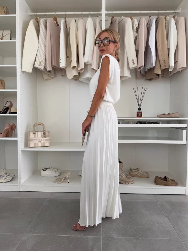 A woman wearing a structured sleeveless top with high-waisted pleated wide-leg pants.