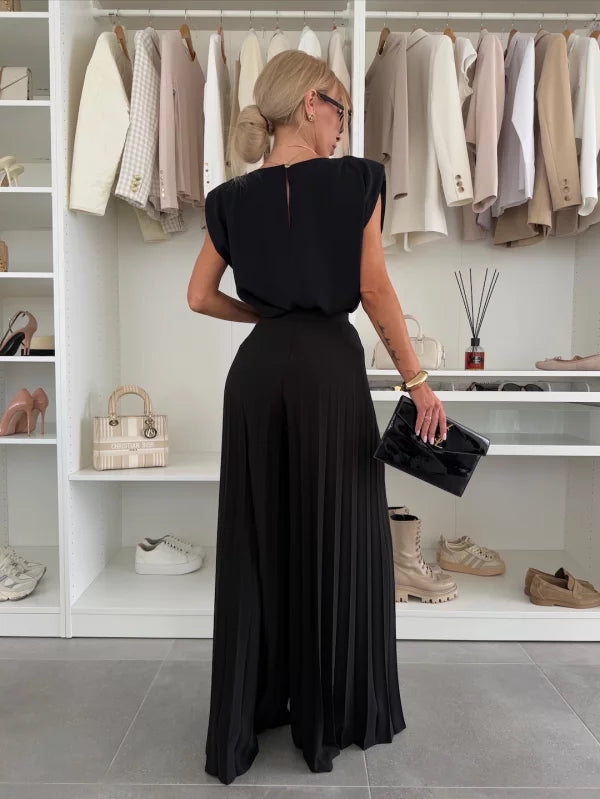 A woman wearing a structured sleeveless top with high-waisted pleated wide-leg pants.