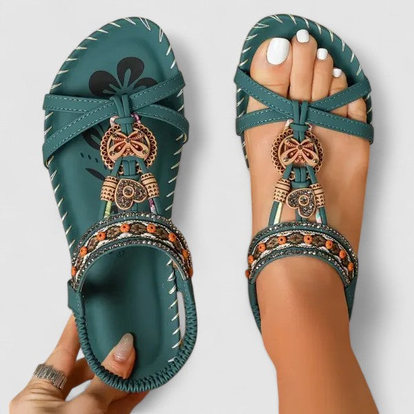 A woman walking comfortably outdoors in cushioned wide-fit orthopaedic sandals with a beaded T-strap and stretch slingback.