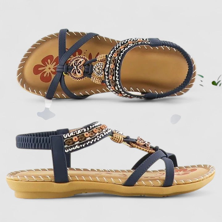 A woman walking comfortably outdoors in cushioned wide-fit orthopaedic sandals with a beaded T-strap and stretch slingback.
