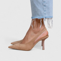 A woman wearing beige pointed slingback stilettos with a slim high heel.