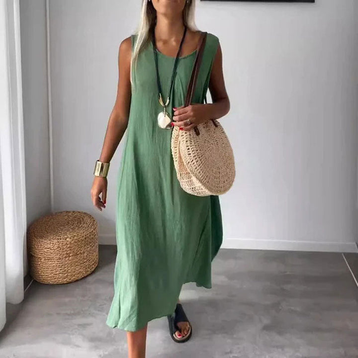 Woman wearing the Denise™ sleeveless flowing maxi dress with side pockets, relaxing outdoors on a warm day.