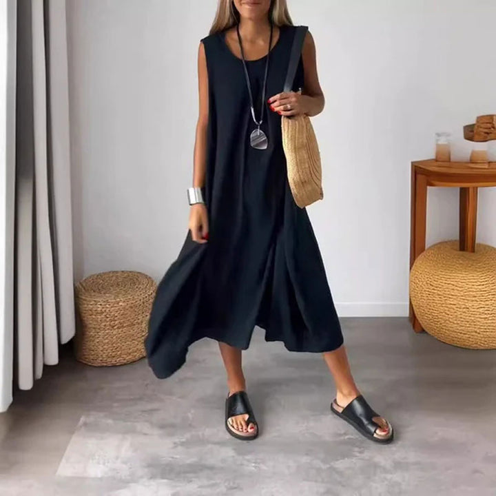Woman wearing the Denise™ sleeveless flowing maxi dress with side pockets, relaxing outdoors on a warm day.