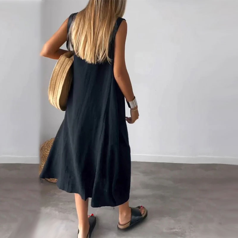 Woman wearing the Denise™ sleeveless flowing maxi dress with side pockets, relaxing outdoors on a warm day.