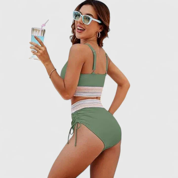 A woman wearing an elegant matching bikini set with a bold print, relaxed and confident on the beach.
