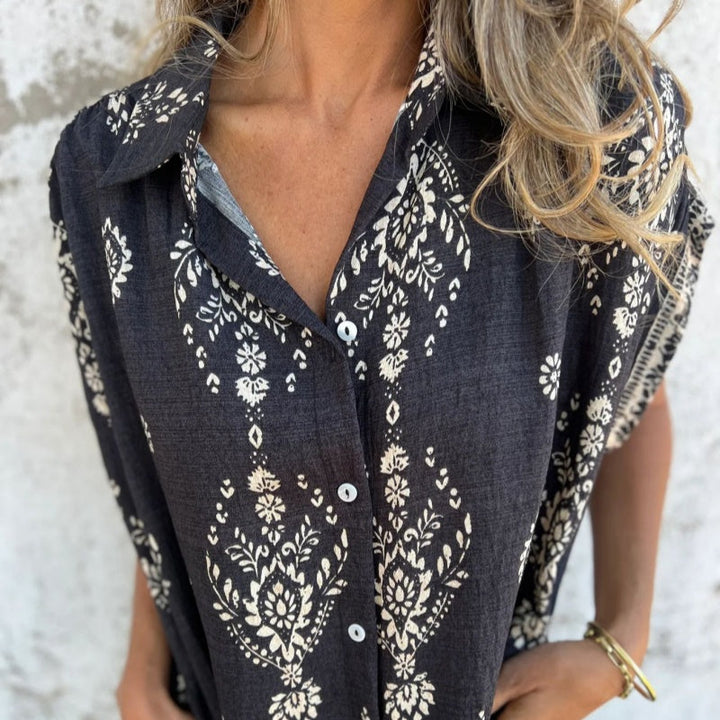 Woman wearing the Isabelle vintage print shirt dress with a button front and soft collar, standing in warm daylight.