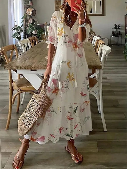 Woman wearing the Jacqueline™ boho maxi dress with fringe details and a V-neckline, relaxed in a warm outdoor setting.
