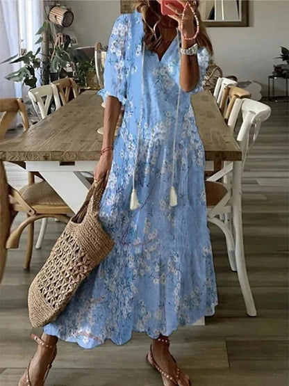 Woman wearing the Jacqueline™ boho maxi dress with fringe details and a V-neckline, relaxed in a warm outdoor setting.