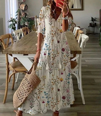 Woman wearing the Jacqueline™ boho maxi dress with fringe details and a V-neckline, relaxed in a warm outdoor setting.