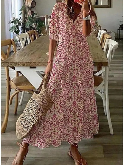 Woman wearing the Jacqueline™ boho maxi dress with fringe details and a V-neckline, relaxed in a warm outdoor setting.