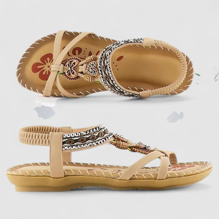 A woman wearing black beaded boho sandals with braided straps, a golden medallion and a stretchy slingback.